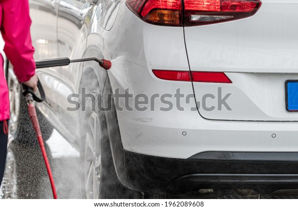 woman washing car with pressure washer at\
self-service car wash station, selective\
focus