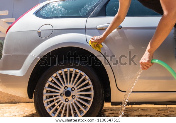 Woman washing\
the car in the yard under the\
sun