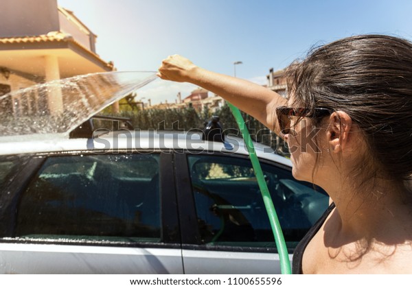 Woman washing
the car in the yard under the
sun