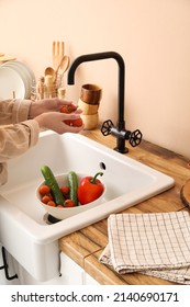 Woman washing cherry tomatoes over sink in kitchen - Shutterstock ID 2140690171