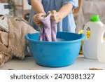 Woman washing clothes in plastic basin on white table