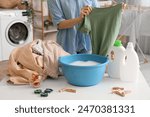 Woman washing clothes in plastic basin on white table