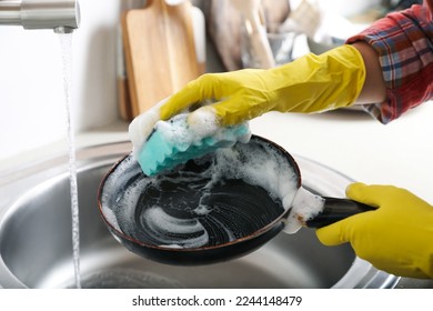 Woman washing dirty frying pan in sink indoors, closeup - Powered by Shutterstock