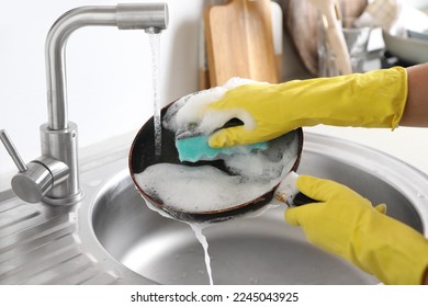 Mujer lavando sartén sucia en el lavabo en el interior, en el armario