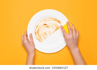 Woman washing dirty plate on orange background