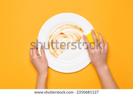 Woman washing dirty plate on orange background