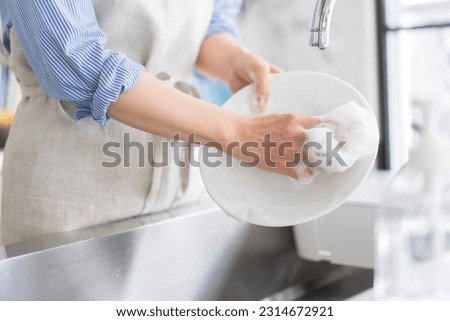 A woman is washing the dishes in the kitchen. 