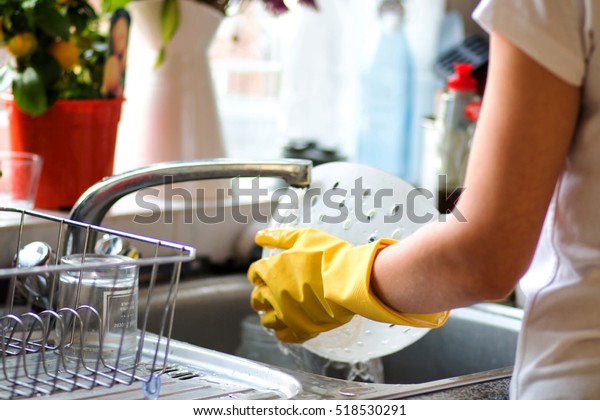 Woman washing dishes in the kitchen. Close\
up of  woman hand. Housewife clean\
dishes.