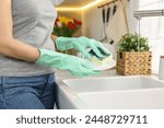 Woman washing dishes in kitchen sink, closeup. Cleaning chores