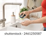 Woman washing dishes in kitchen sink, closeup. Cleaning chores