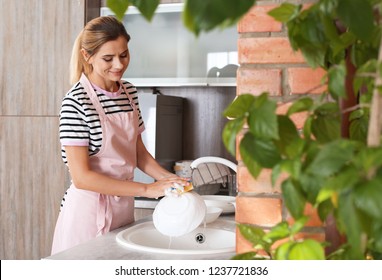 Woman washing dishes in kitchen sink. Cleaning chores