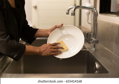 Woman Washing The Dishes In Kitchen Sink In The Restaurant