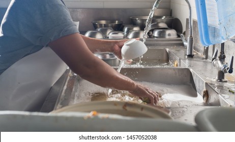 Woman Washing Dishes On Sink At Restaurant