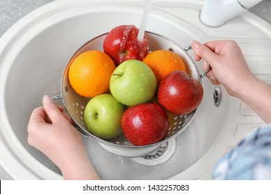 Woman washing fresh fruits in colander under water, closeup