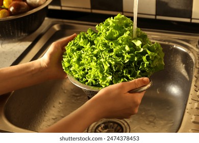 Woman washing fresh lettuce leaves in metal colander, closeup - Powered by Shutterstock