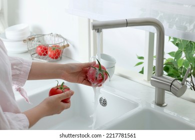 Woman washing fresh ripe tomatoes under tap water in kitchen, closeup - Powered by Shutterstock