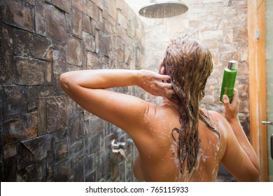 Woman Washing Hair In Shower And Holding Shampoo Bottle