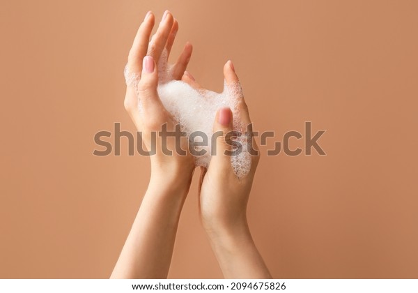 Woman washing\
hands with soap on color\
background