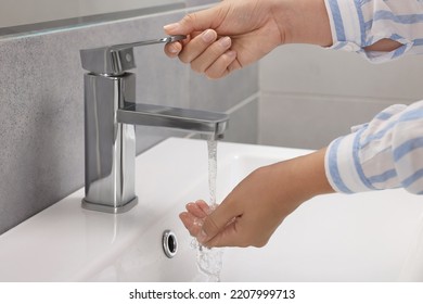 Woman washing hands with water from tap in bathroom, closeup - Shutterstock ID 2207999713