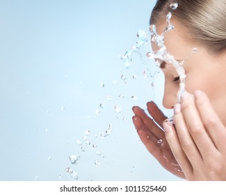 A woman is washing her face with cold water, cleaning skin after makeup, using anti acne or anti aging agent, pampering and beauty care concept, over blue clear background