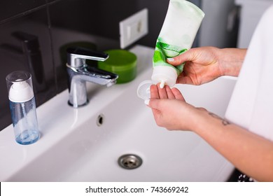 Woman washing up her face with foam cleanser in the morning