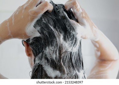 Woman is washing her hair with shampoo - Shutterstock ID 2153248397