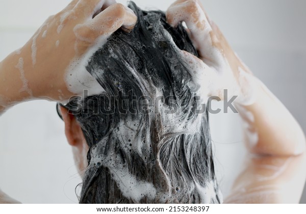 Woman is washing her\
hair with shampoo