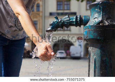 woman washing her hands in a public water pump in the city, female tourist refreshment herself in city fountain