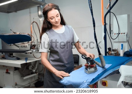 Woman washing house worker carefully ironing shirt on ironing board