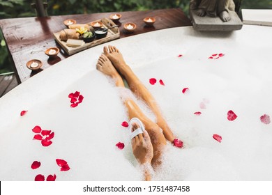 Woman washing legs in bath tub with foam bubbles and use natural loofah sponge. Spa treatment, body care, romantic mood. - Powered by Shutterstock