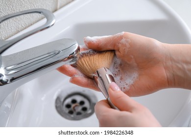 Woman washing makeup brush under water