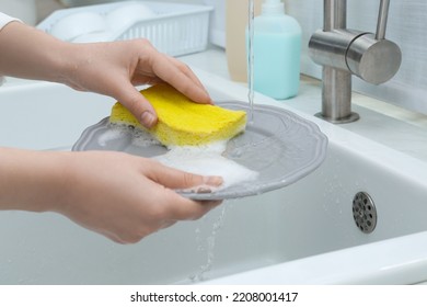 Woman Washing Plate Above Sink In Kitchen, Closeup