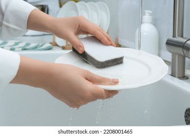 Woman Washing Plate Above Sink In Kitchen, Closeup