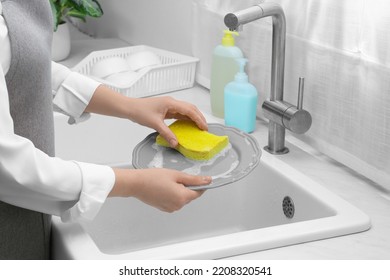 Woman Washing Plate Above Sink In Kitchen, Closeup