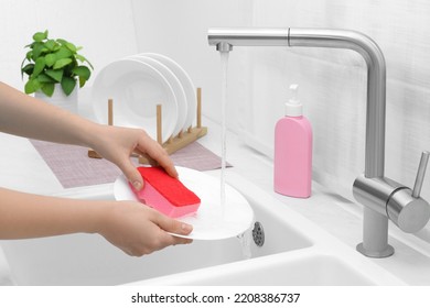 Woman Washing Plate Above Sink In Kitchen, Closeup