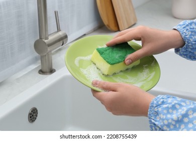 Woman Washing Plate Above Sink In Kitchen, Closeup