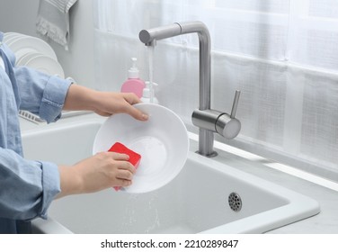 Woman Washing Plate Above Sink In Kitchen, Closeup