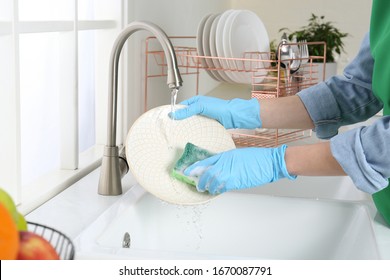 Woman washing plate in modern kitchen, closeup