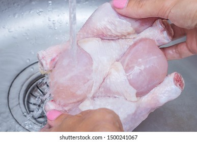 Woman Washing Raw Frozen Hen In Kitchen Sink. Cooking Chicken At Home. Close-up, Selective Focus.