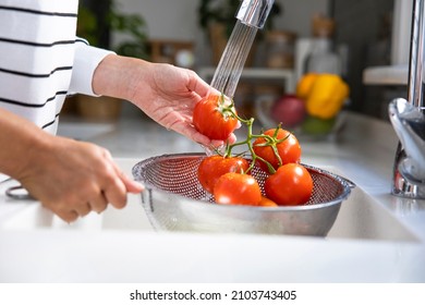 Woman washing vegetables on kitchen counter. Healthy foods