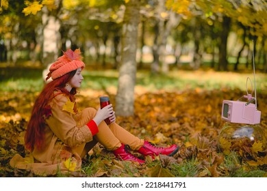 Woman Watches A Small Retro TV On The Park. Autumn Outdoor Recreation. Concept