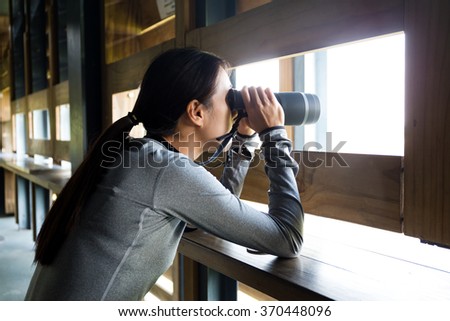 Woman watching bird though binocular