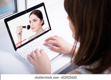 Woman Watching Blog Video About Make Up On Laptop At Home