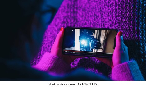 Mujer viendo una película de crimen en el teléfono móvil con un servicio imaginario de reproductor de video. Secuencia de películas en línea con smartphone. 