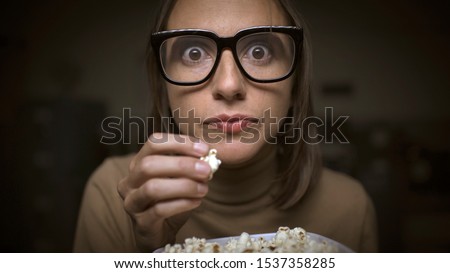 Woman watching movies and eating popcorn, she is addicted and glued to the screen Stock fotó © 