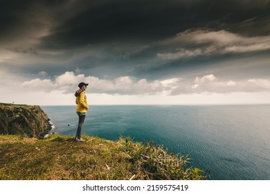 Woman Watching The Ocean With A Lighthouse On The Back, Azores Island.