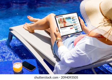 Woman watching online videos on tablet while relaxing by the pool - Powered by Shutterstock