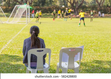 woman watching a school boy soccer game on a sunny day