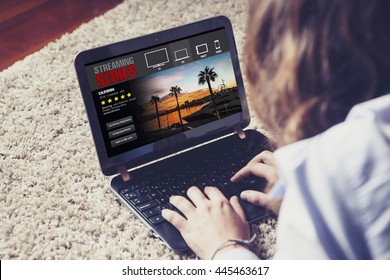 Woman watching streaming tv series in a laptop computer, lying down on the floor at home.