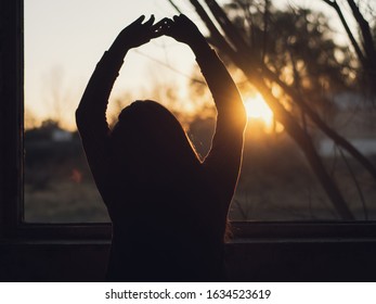 Woman Watching The Sunrise Just Raised From Her Window